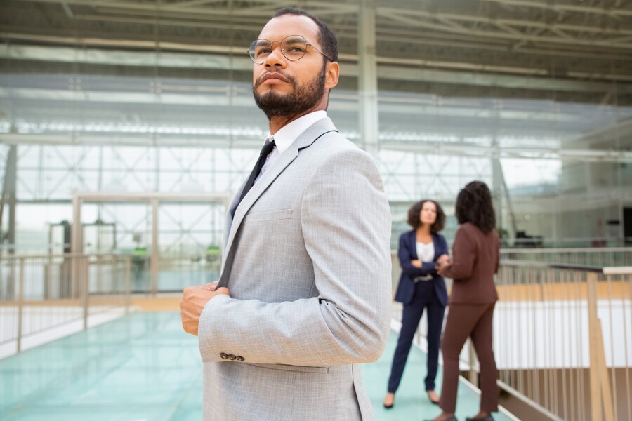  Black man in a suit and glasses exuding confidence, standing with a composed expression that reflects leadership and professionalism.