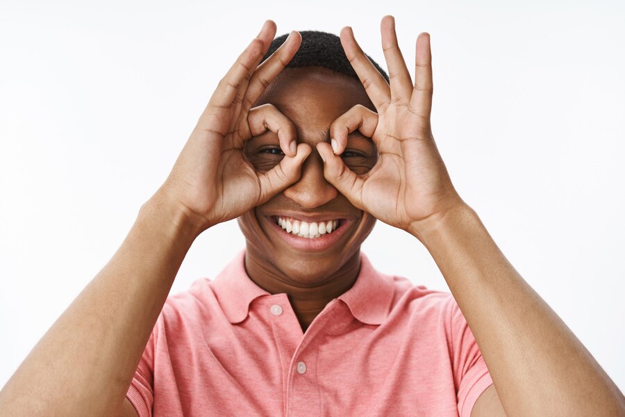 Handsome young African-American with pink polo Tshirt using his hands as a goggle and smiling